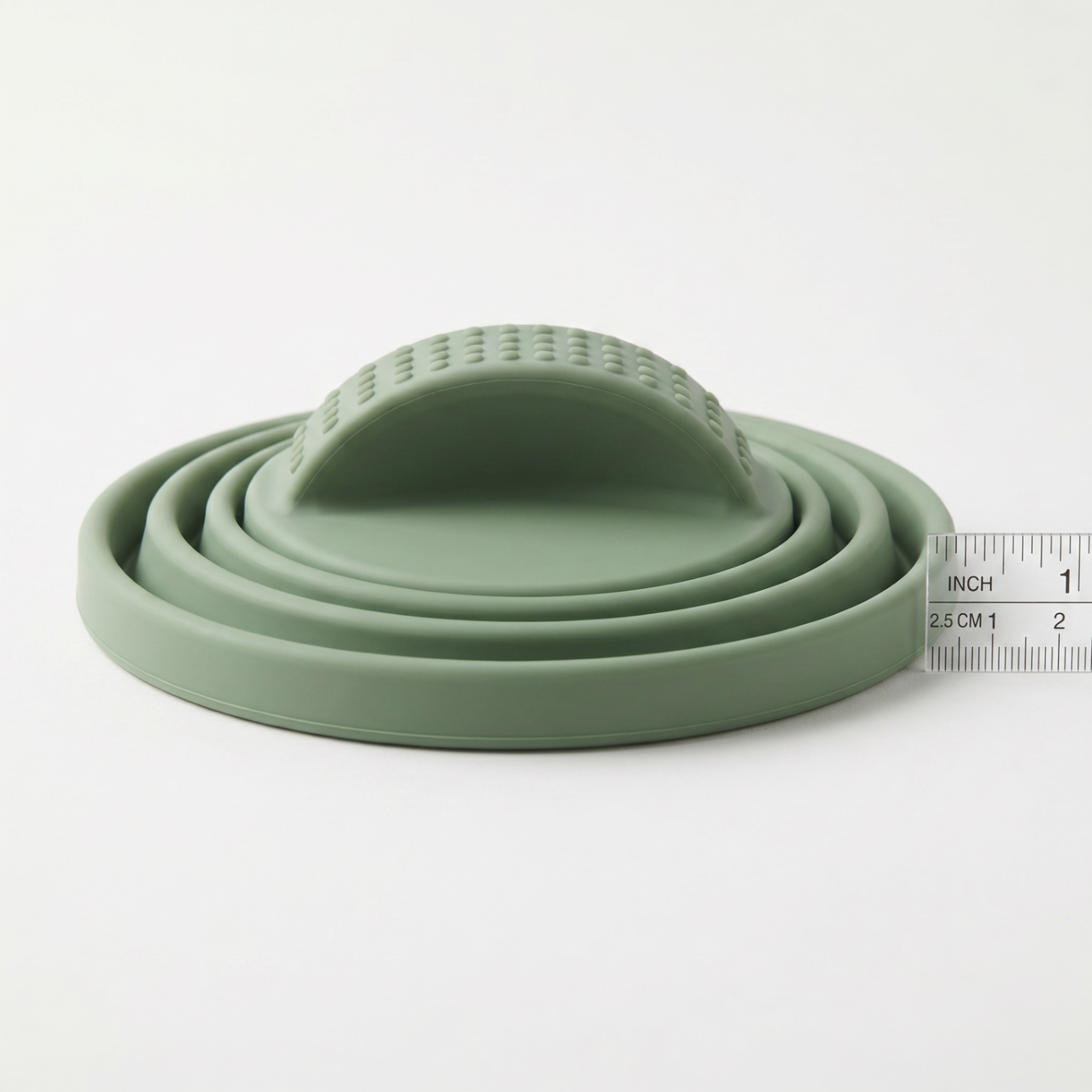 Collapsed sage green Circular microwave cover stored flat in a kitchen drawer